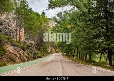 Vider la route d'asphalte courbée menant entre la forêt verte et les montagnes en été nuageux Banque D'Images