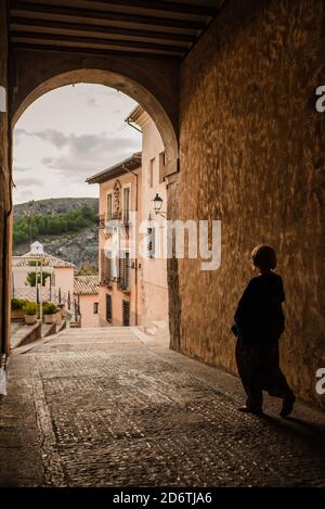 Vue arrière d'une femelle touristique méconnue se promenant à travers l'arcade de Bâtiment médiéval en pierre tout en explorant les rues de la ville de Cuenca dans Espagne Banque D'Images