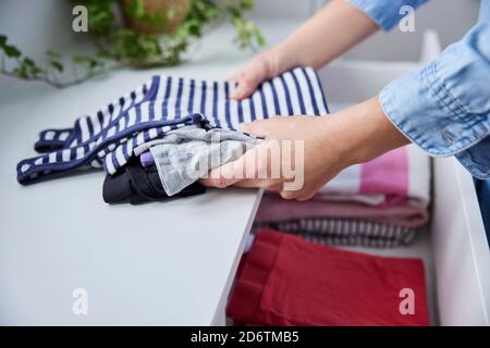 Gros plan de la femme qui replie les vêtements et les mordant Dans les tiroirs Banque D'Images