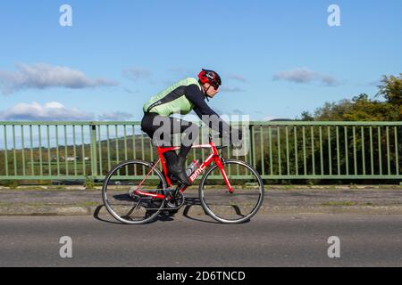Cycliste de race masculine à cheval BMC fibre de carbone léger vélo de route sportif sur la route de campagne traversant le pont d'autoroute dans la campagne du Lancashire, Royaume-Uni Banque D'Images