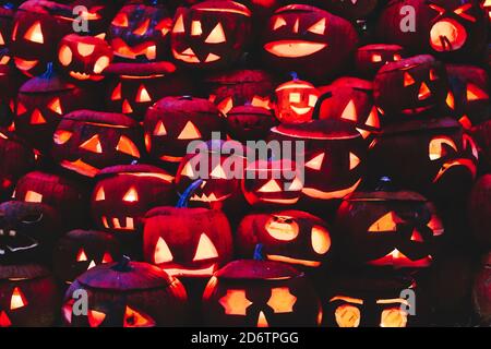 Arrière-plan de citrouilles d'Halloween sculptées et illuminées dans le noir. Banque D'Images