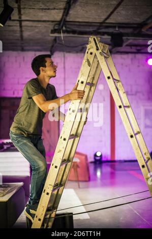 Technicien en éclairage de théâtre ingénieur en électricité qui ajuste la mise au point des éléments d'éclairage de la scène arrière. Des spots dans le théâtre. Derrière la scène Banque D'Images