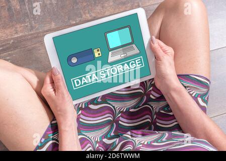 Femme assise sur le sol avec une tablette montrant les données concept de stockage Banque D'Images