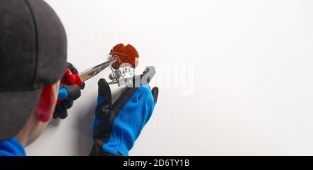 électricien installant un interrupteur d'éclairage sur un mur peint à l'aide d'un tournevis. Homme installant l'interrupteur d'éclairage après rénovation. Banque D'Images