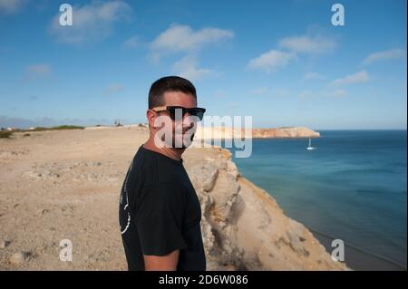 Jeune homme qui donne sur l'océan au coucher du soleil au Portugal en été Banque D'Images