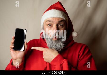 le père noël montre son téléphone cellulaire de surprise Banque D'Images