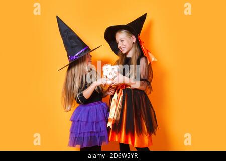 Deux petits sorcières en costumes d'halloween sur fond orange Banque D'Images