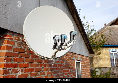 La parabole satellite est fixée au mur de la maison. Une installation de télévision par satellite sous le toit Banque D'Images