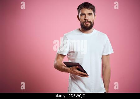 L'homme annonce une tablette sur fond rose codes espace vue rognée des émotions t-shirt blanc modèle nouvelles technologies Banque D'Images