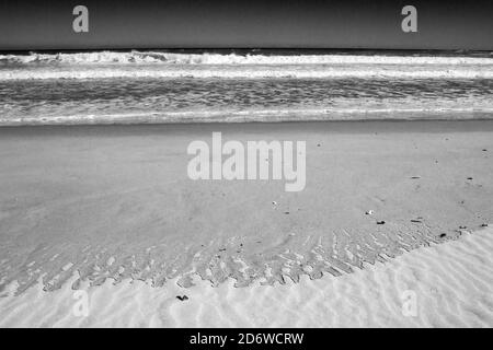 Motifs laissés sur une plage de sable après un remake de la vague en Monochrome, photographié sur la côte ouest de l'Afrique du Sud Banque D'Images