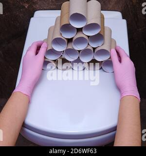 Les mains dans des gants de protection tiennent des rouleaux vides de papier toilette, en gros plan. Concept de pénuries de produits dues à des achats pendant la crise Banque D'Images