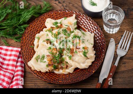 Pierogi ou boulettes farcies à la pomme de terre servies avec de l'oignon frit et de la vodka. Cuisine russe et polonaise Banque D'Images