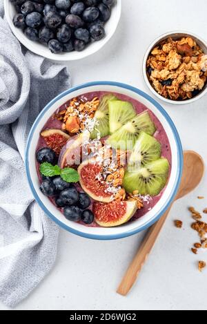 Bol à smoothie végétalien Superfood avec garnitures aux fruits et au granola. Fond en béton gris, vue de dessus Banque D'Images