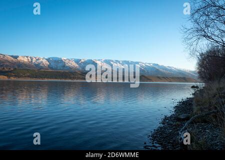 Montagnes enneigées sur la chaîne de Pise, regardant à travers le lac Dunstan, Cromwell, Central Otago, South Island, Nouvelle-Zélande Banque D'Images