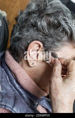 Femme âgée holding aide auditive. Banque D'Images