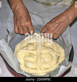 Les mains d'une femme au foyer âgée qui s'agenouillent un gâteau de fête - du pain pour les célébrations à venir. Le pain est ensuite cuit au four. Banque D'Images