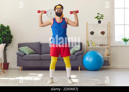 Drôle gai barbu homme faisant des entraînements sportifs avec des haltères à la maison dans le salon. Banque D'Images