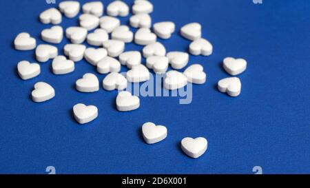 Des pilules en forme de coeur ont été déversées de la bouteille sur la surface bleue de la table à la pharmacie. Arrière-plan isolé. Arrière-plan bleu Banque D'Images