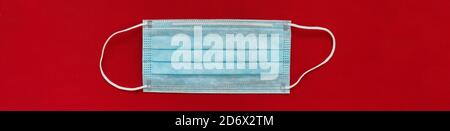 Corona virus visage masque vue de dessus avec arrière-plan rouge bannière panoramique. Concept COVID-19 Banque D'Images