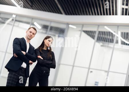 Un homme d'affaires et femme debout dos à dos avec des sourires sur leurs visages Banque D'Images