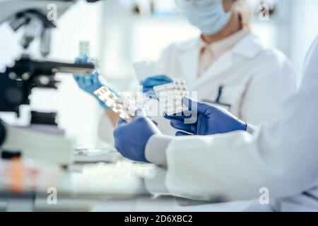 scientifiques avec des échantillons de nouveaux médicaments assis à une table de laboratoire. Banque D'Images