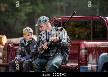 Père dans un chapeau et son fils assis dans une voiture après la chasse. Banque D'Images