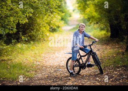 Garçon fait du vélo dans la forêt d'automne Banque D'Images