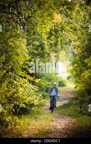 Garçon fait du vélo dans la forêt d'automne Banque D'Images