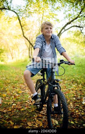 Garçon fait du vélo dans la forêt d'automne Banque D'Images