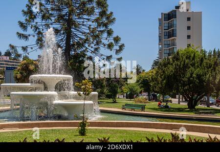 Vina Del Mar, Chili - 8 décembre 2008 : grande fontaine blanche dans le parc vert de Plaza Mexico avec grand bâtiment à côté. Arbres, pelouses et quelques personnes. Banque D'Images