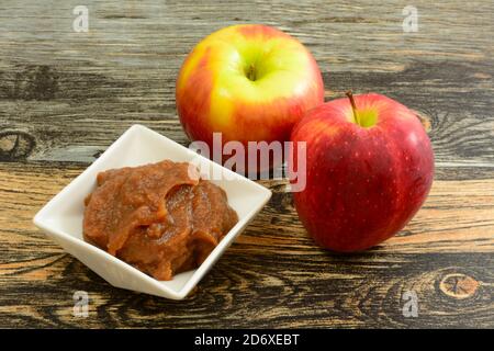 Beurre de pomme dans un bol blanc et pomme et rouge croustillants de délicieuses pommes de pomme sur la table Banque D'Images