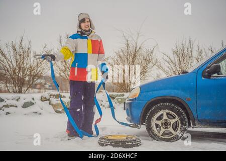 Homme avec crochets de corde de remorquage près de la voiture remorquée Banque D'Images