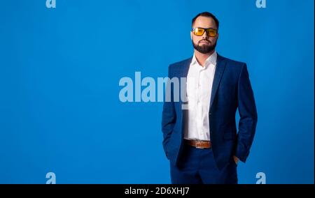 Jeune homme dans un costume bleu classique sur un bleu arrière-plan Banque D'Images
