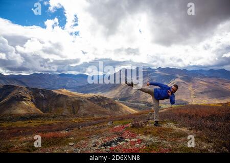 Homme Kicking et la pratique des arts martiaux sur le dessus d'un Montagne Banque D'Images