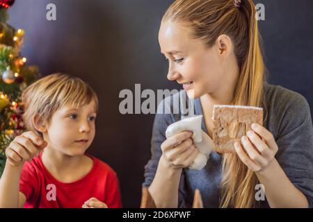 Jeune mère et enfant faisant maison de pain d'épice la veille de Noël Banque D'Images