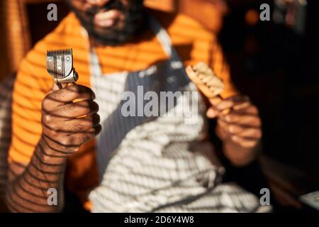 Afro-américain tenant une tondeuse et une brosse vintage Banque D'Images