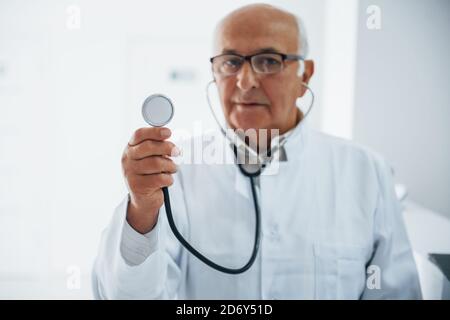 Portrait d'un médecin senior avec stéthoscope et uniforme blanc qui se trouve dans la clinique Banque D'Images