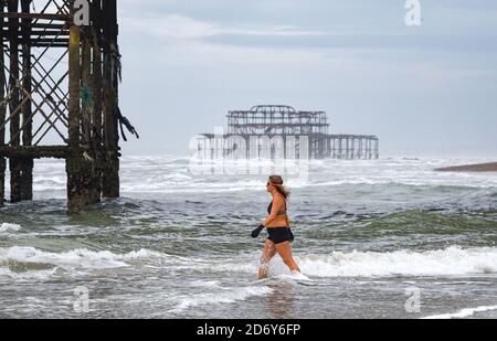 Brighton, Royaume-Uni, le 20 octobre 2020 - UN nageur entre dans la mer à Brighton lors d'une matinée pleine de brise mais de lumière à marée basse . Des conditions humides et venteuses sont prévues pour les prochains jours dans toute la Grande-Bretagne comme Storm Barbara approche de l'Europe : crédit Simon Dack / Alamy Live News Banque D'Images