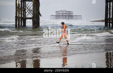 Brighton, Royaume-Uni, le 20 octobre 2020 - UN nageur entre dans la mer à Brighton lors d'une matinée pleine de brise mais de lumière à marée basse . Des conditions humides et venteuses sont prévues pour les prochains jours dans toute la Grande-Bretagne comme Storm Barbara approche de l'Europe : crédit Simon Dack / Alamy Live News Banque D'Images