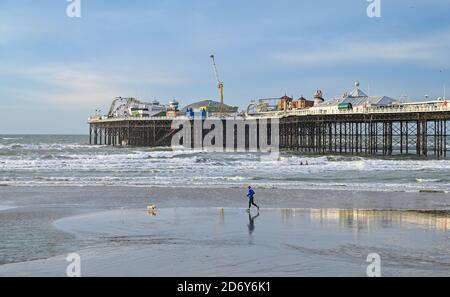 Brighton, Royaume-Uni, le 20 octobre 2020 - UN coureur sur la plage de Brighton profite de la brise mais de la lumière du matin à marée basse. Des conditions humides et venteuses sont prévues pour les prochains jours dans toute la Grande-Bretagne comme Storm Barbara approche de l'Europe : crédit Simon Dack / Alamy Live News Banque D'Images