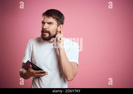 L'homme annonce une tablette sur fond rose codes espace vue rognée des émotions t-shirt blanc modèle nouvelles technologies Banque D'Images