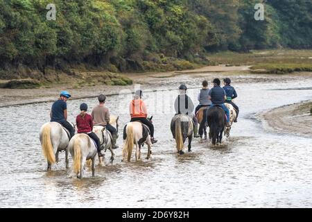 Un groupe de cavaliers longeant la rivière Gannel à marée basse à Newquay, en Cornouailles. Banque D'Images