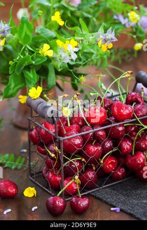 Cerises mûres fraîches dans un panier en métal sur fond de bois Banque D'Images