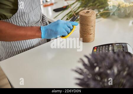 Fleuriste utilisant la corde pour bouquets au terminal de pos Banque D'Images