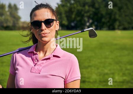 Femme avec un club de golf debout à l'extérieur Banque D'Images