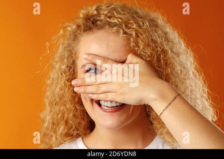 Souriante positive jeune femme qui peep à travers ses doigts fermer les yeux avec sa paume Banque D'Images