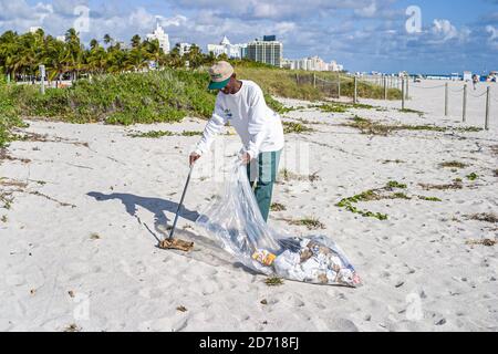 Miami Beach Florida, Atlantic Ocean Shore, employé de la ville nettoie le sable public de plage, Black African homme collecte déchets litière, Banque D'Images