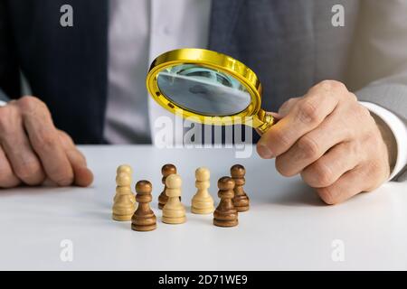 recherche d'employés, agence de recrutement concept. homme d'affaires avec loupe sur pions d'échecs Banque D'Images