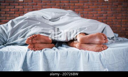 Vue rapprochée des pieds de couple qui dort ensemble dans la chambre à coucher le matin Banque D'Images