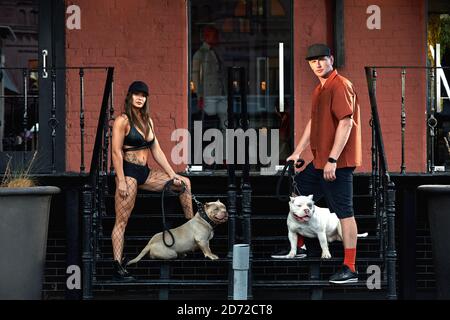 jeune homme et femme élégamment habillés avec une figure athlétique avec deux chiens intimidateurs américains dans les rues de la ville Banque D'Images